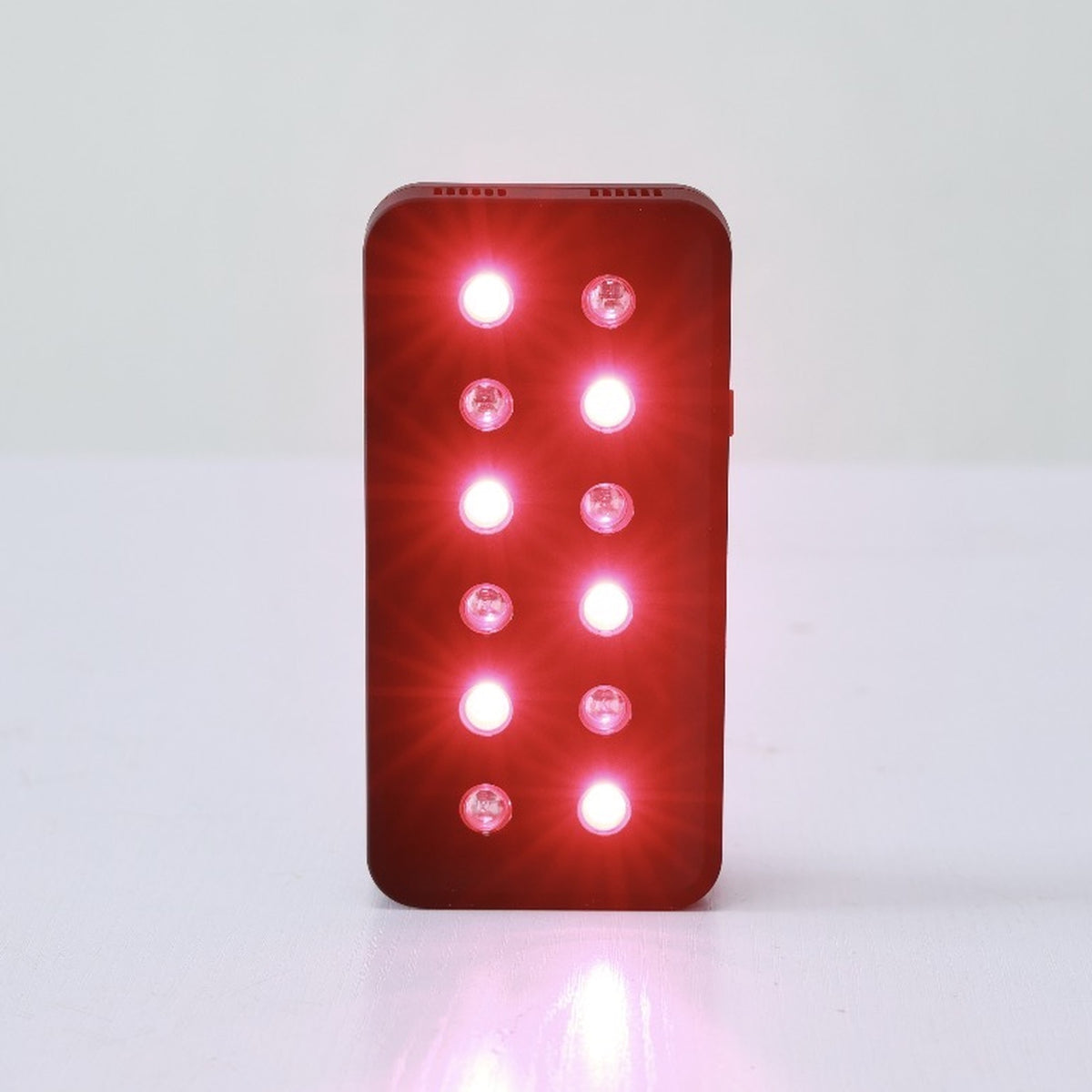 The Heal For You Light handheld device standing upright with all twelve LEDs lit red