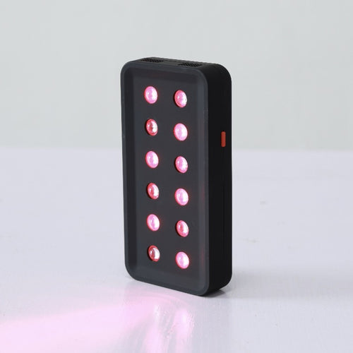 The device at an angle, twelve LEDs lit, casting red light onto the surface